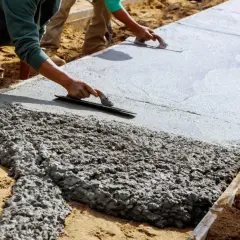 Pracownicy wygładzają świeży beton. Zastanawiasz się, ile betonu z jednego worka cementu? To zależy od proporcji!