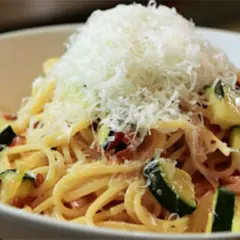 Spaghetti mit Zucchini und Speck, gekrönt mit frisch geriebenem Parmesan. Eine köstliche Zucchini Carbonara.