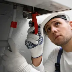 Fachowiec w białej rękawicy naprawia instalację, bo piec nie grzeje wody w bojlerze.