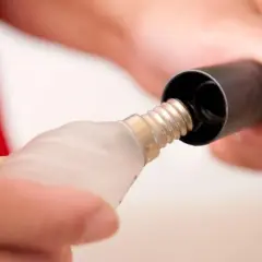 Manos ajustando el tamaño del casquillo de una bombilla a un accesorio negro.