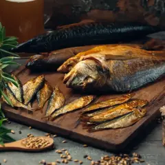 Wędzone ryby na desce, różne gatunki. Zastanawiasz się, jak długo wędzić ryby? Oto apetyczna inspiracja.