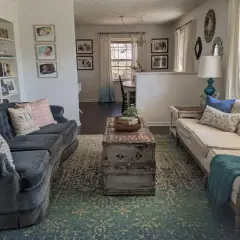 A living room with two sofas, a vintage trunk coffee table, and a patterned rug. This space shows how to brighten a dark room with light-colored furniture and ample natural light.