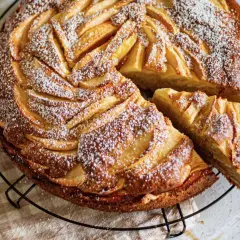 Gâteau mascarpone pommes, une tranche coupée, saupoudré de sucre glace. Un délice doré et moelleux.