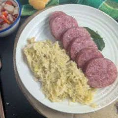 Piatto con fette di cotechino fresco e crauti, accompagnato da un'insalata di verdure e pane. Perfetto per la cottura.