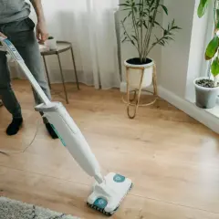 Osoba myje podłogę z paneli mopem parowym. Czy mopem parowym można myć panele? Tak, ten sprzęt świetnie sobie radzi z czyszczeniem.