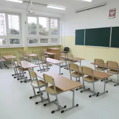 Pusta sala lekcyjna z ławkami i krzesłami, jakby czekająca na uczniów, kiedy wprowadzono gimnazjum w Polsce.