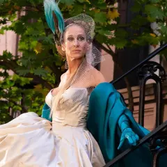 Carrie Bradshaw w białej sukni i turkusowym płaszczu, z welonem na głowie, siedzi na schodach. I tak po prostu.