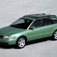 Zielony kombi Audi A4 B5 z relingami dachowymi i szyberdachem, zaparkowany na betonowej nawierzchni.
