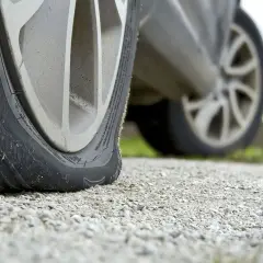 Opona samochodowa leży płasko na żwirze, sygnalizując awarię.