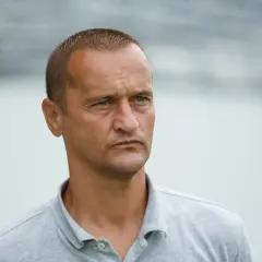 Dariusz Dźwigała w szarym polo, zamyślony, patrzy w bok.