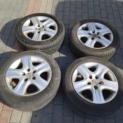 Cztery felgi strukturalne Opel z oponami leżą na chodniku.