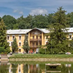 Żółty dworek nad stawem, otoczony drzewami, to idealne miejsce, by sprawdzić, co warto zobaczyć w Nałęczowie.