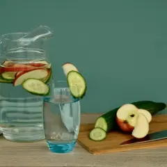 Erfrischendes Apfelwasser selber machen: Gurken- und Apfelscheiben in einer Karaffe und einem Glas.