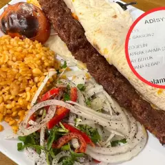 Talerz z tureckim kebebabem, ryżem, sałatką i rachunkiem.