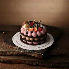 En vacker tårta med macarons, bär och chokladdekorationer, serverad på ett rustikt träfat.