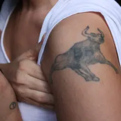 Mały tatuaż byk na ramieniu, symbol siły i odwagi.