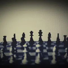 Czarne figury szachowe ustawione na planszy, gotowe do gry. Każdy ruch to element skomplikowanej taktyki szachowej.