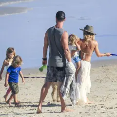 Chris Hemsworth z dziećmi i żoną na plaży. Rodzina cieszy się słońcem i piaskiem.