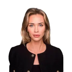 Isabella Jedler, en kvinna med blont hår och blå ögon, bär en svart kavaj med gulddetaljer.