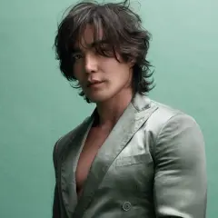 Ludi Lin, star de films et séries tv, pose dans un costume satiné sur fond vert menthe.