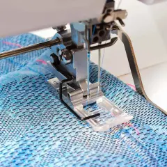 Sewing machine creating a coverstitch hem on blue patterned fabric.