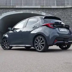 Ciemnoszary Toyota Yaris Hybrid z nowoczesnymi felgami stoi przed betonowym tunelem.