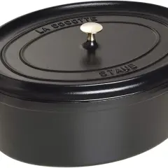 Schwarzer ovaler Schmortopf von Staub mit goldfarbenem Griff. Perfekt für langsam gegarte Gerichte, was ein Schmortopf eben ist.
