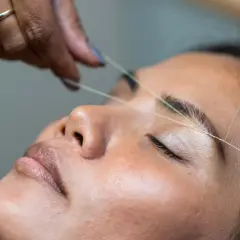 En tråd dras över ögonbrynet för att forma det, en klassisk brow bar-behandling som ger en perfekt brow bar mood.