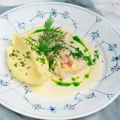 En vällagad torskrygg i ugn serveras med krämigt potatismos och en len sås, toppad med färsk dill och persilja.