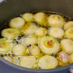 Cipolline in agrodolce in padella con aceto balsamico, che sobbollono in un liquido dorato, pronte per essere gustate.