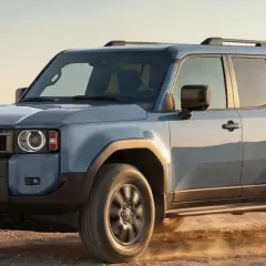 Un Toyota Land Cruiser hdj 100 azul claro avanza por un camino polvoriento, listo para la aventura.