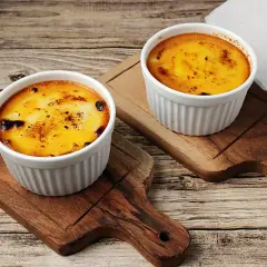 Zwei Portionen Crema Catalana Eis, karamellisiert und auf Holzbrettern serviert.