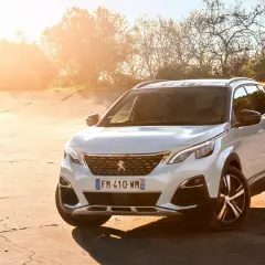Blanco Peugeot 3008 Hybrid4 aparcado en un camino de tierra al atardecer.