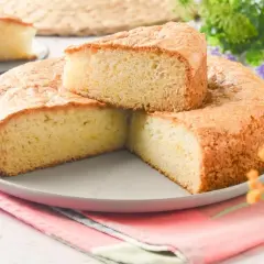 Bizcocho sin huevo esponjoso y dorado, servido en plato gris con servilleta colorida. Perfecto para un postre ligero.