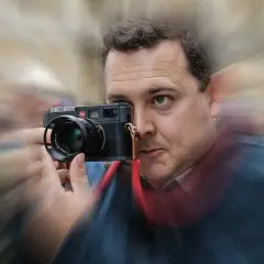Man with Leica camera, possibly contemplating the best focal length for street photography.