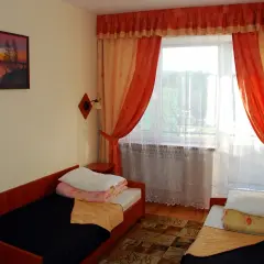 Pokój w sanatorium Plon Polańczyk. Dwa łóżka, okno z pomarańczowymi zasłonami, obraz na ścianie.