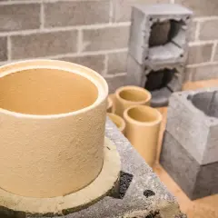 Ceramiczne wkłady kominowe w różnych rozmiarach, gotowe do montażu. Obok betonowe elementy konstrukcyjne.