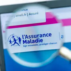Loupe sur l'écran d'un ordinateur affichant le site ameli.fr, logo de l'Assurance Maladie. Une lettre demande d'ouverture des droits à l'assurance maladie est en cours de consultation.