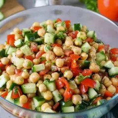 Frischer Kichererbsen Gurken Salat in einer Glasschüssel, garniert mit Petersilie und Tomaten.