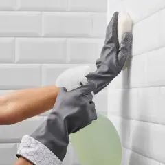 Rękawiczki i gąbka pomagają pozbyć się grzyba z fug na białych kafelkach.