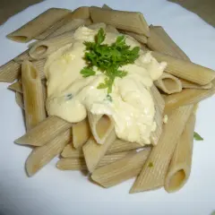 Penne z kremowym sosem pomidorowym z ricottą, udekorowane natką pietruszki. Pyszne danie gotowe w kilka minut.