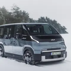 Nowy Kia PV5 w zimowej scenerii. Rodzina bawi się na śniegu w tle.