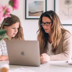 Mama uczy córkę, jak nauczyć się cierpliwości, wspólnie pracując przy laptopie.