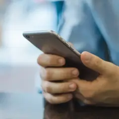 Mężczyzna trzyma telefon, zastanawiając się, jak zacząć rozmowę na Badoo.