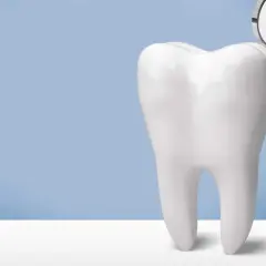 Biały ząb obok lusterka dentystycznego. Po piaskowaniu zębów uśmiech jest olśniewający.