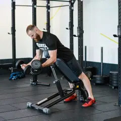 Mężczyzna wykonuje ćwiczenie incline dumbbell curl na ławce skośnej, budując masę mięśniową ramion.