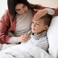 Matka sprawdza gorączkę chorego synka. Opieka na dziecko ile dni trwa, gdy jest chore?