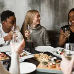Vänner njuter av middag och vin. Perfekt för att ställa 100 roliga frågor och lära känna varandra bättre.
