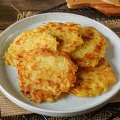 Goldbraune, knusprige Kartoffelpuffer aus gekochten Kartoffeln liegen auf einem Teller. Dazu passt Apfelmus.