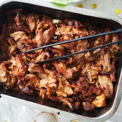 Saftigt, strimlat fläskkött i en ugnsform, redo att serveras. Perfekt för ett gott carnitas recept!